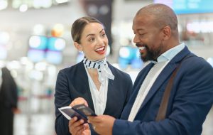 An airport scene with a woman assisting an African businessman during passport inspection, as compliance checks are being reviewed.
