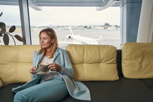 Young lady sitting in the sofa at the airport lounge waiting for the boarding