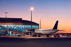 An airplane on the runway being prepared for flight against a vibrant sunset sky.