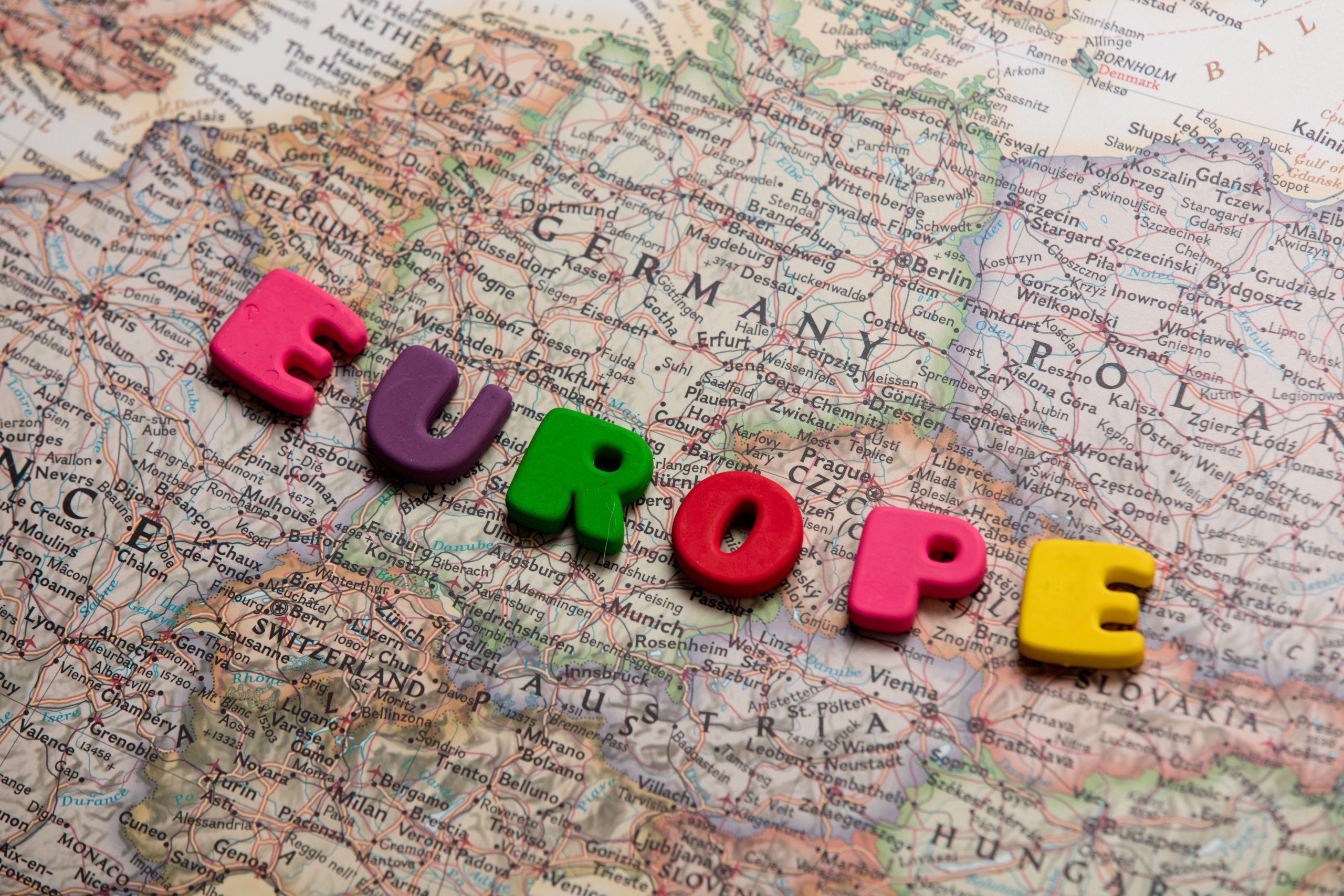 Close-up of a map showing Germany and neighboring countries, overlaid with the word "EUROPE" in pink, purple, green, red, and yellow block letters.