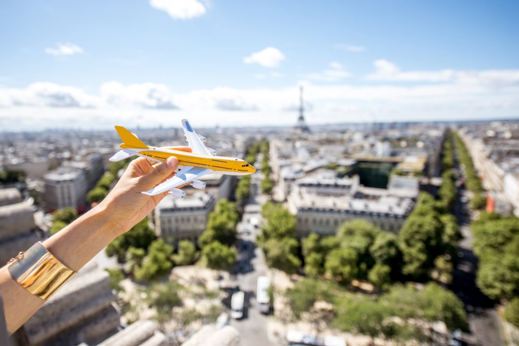 A toy plane "flying" over Paris streets with the Eiffel Tower in the background, symbolizing travel and tourism in France.