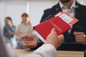 A Meet & Assist agent hands a red passport and boarding passes to a client for fast-track processing through the Entry/Exit System at the airport.