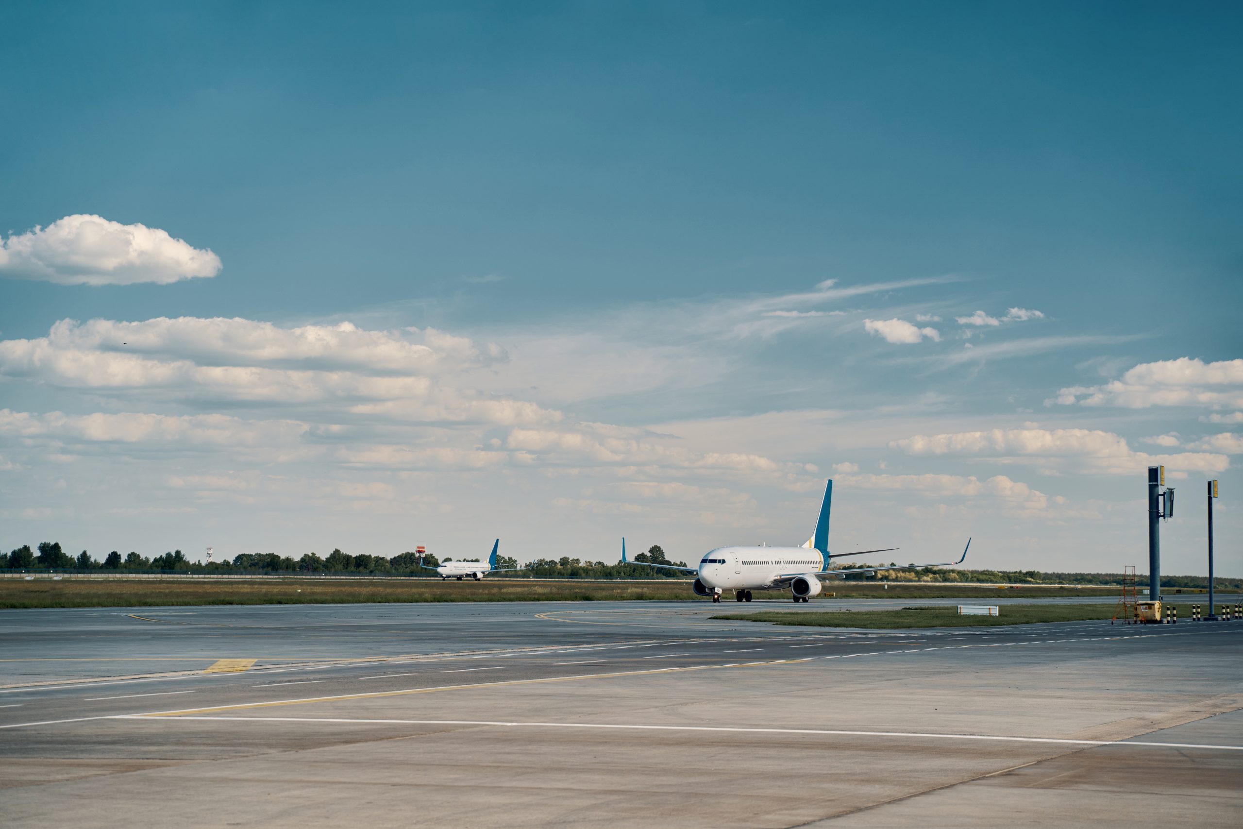 Two beautiful modern large commercial jet airliners parked on an airfield after landing on a sunny day, with clear blue skies and bright daylight.